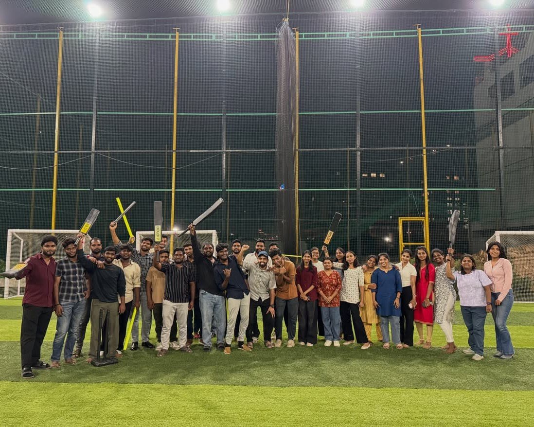 Team posing with cricket bats at an indoor sports ground